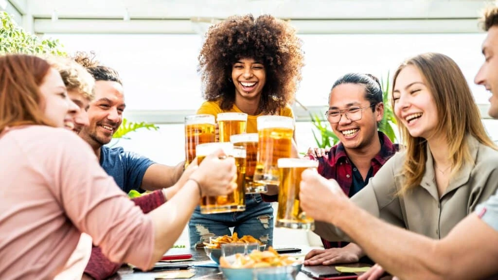 mixed race group of friends toasting beer glasses at brewery pub