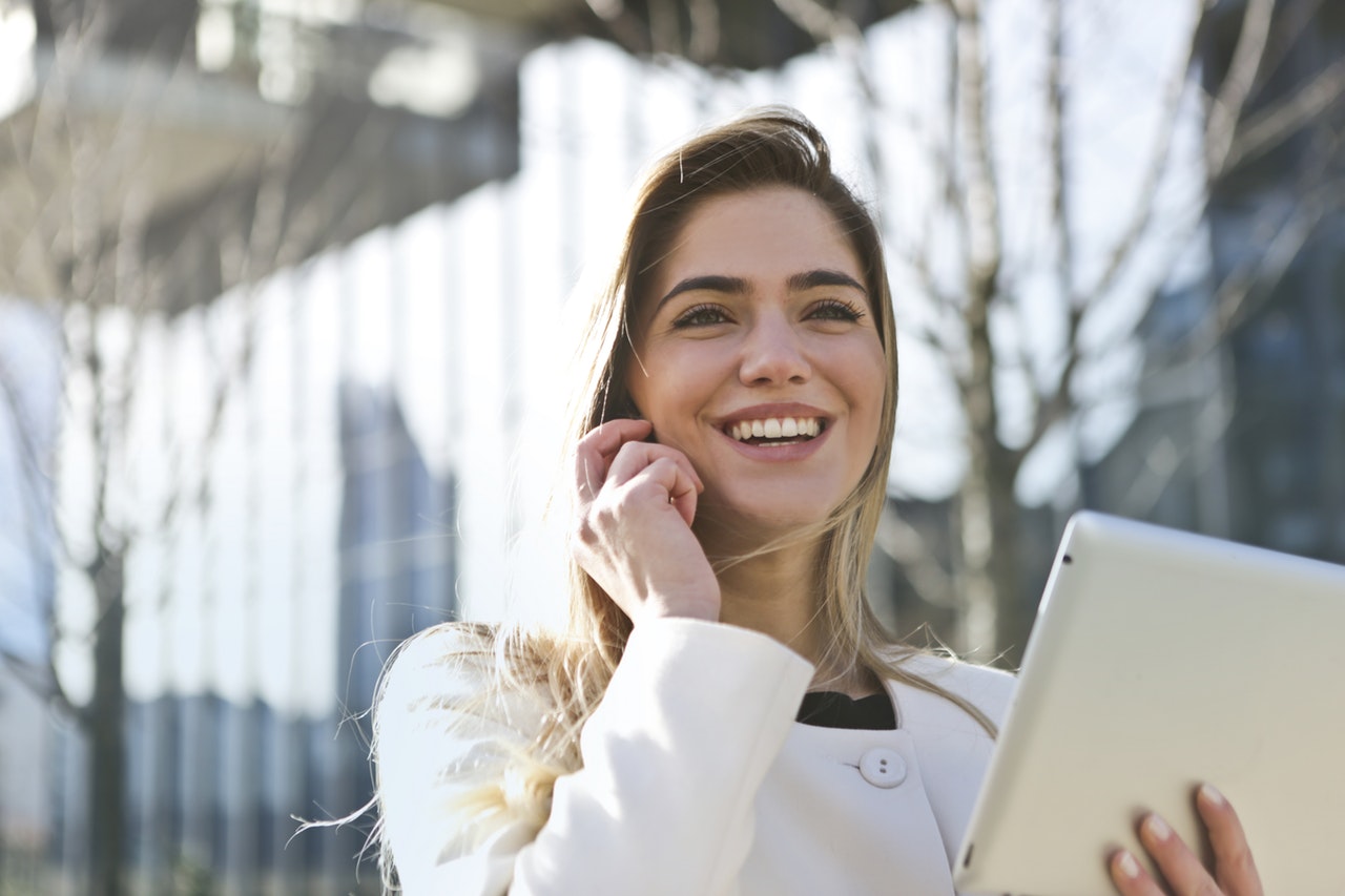woman smiling while talking on the phone and holding a tablet equipped with the latest customer service trends