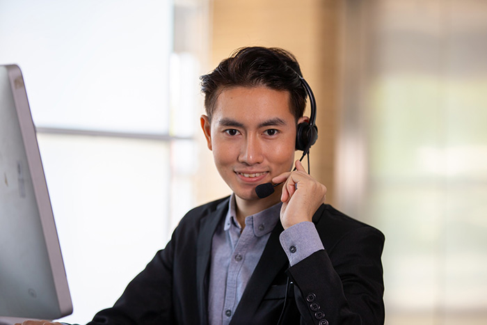 smiling asian businessman consultant wearing microphone headset of customer support phone operator