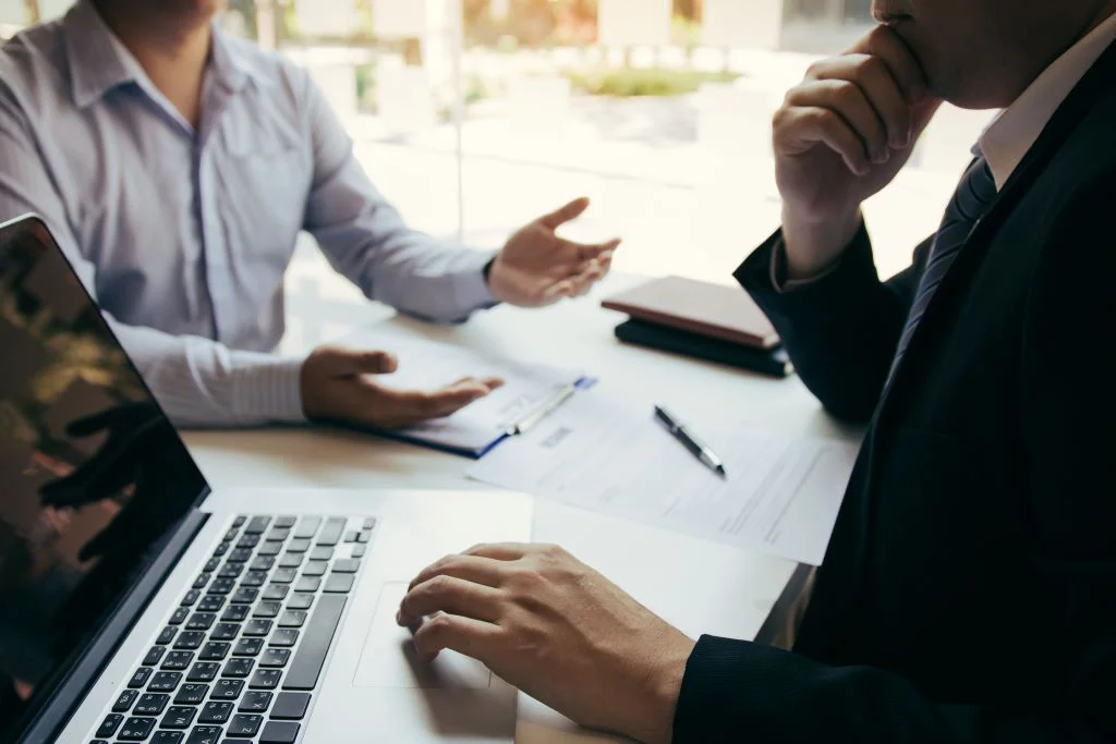 asian young adult sitting at desk across from other man