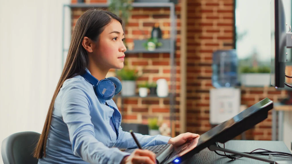 female graphic designer editing photos with tablet for a outsource graphic design work 1 1024x576 1