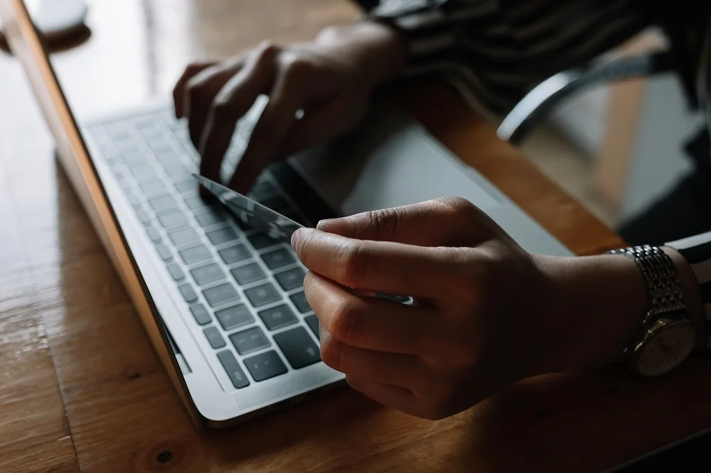 closeup of a woman using a laptop and credit card to pay for her online purchases