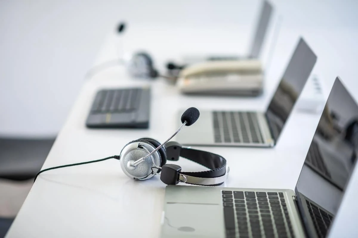 a telemarketing setup with computers and a headphone on a table