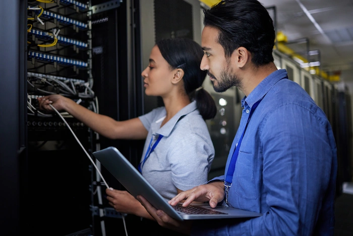 network support man woman in server room using laptop for maintenance