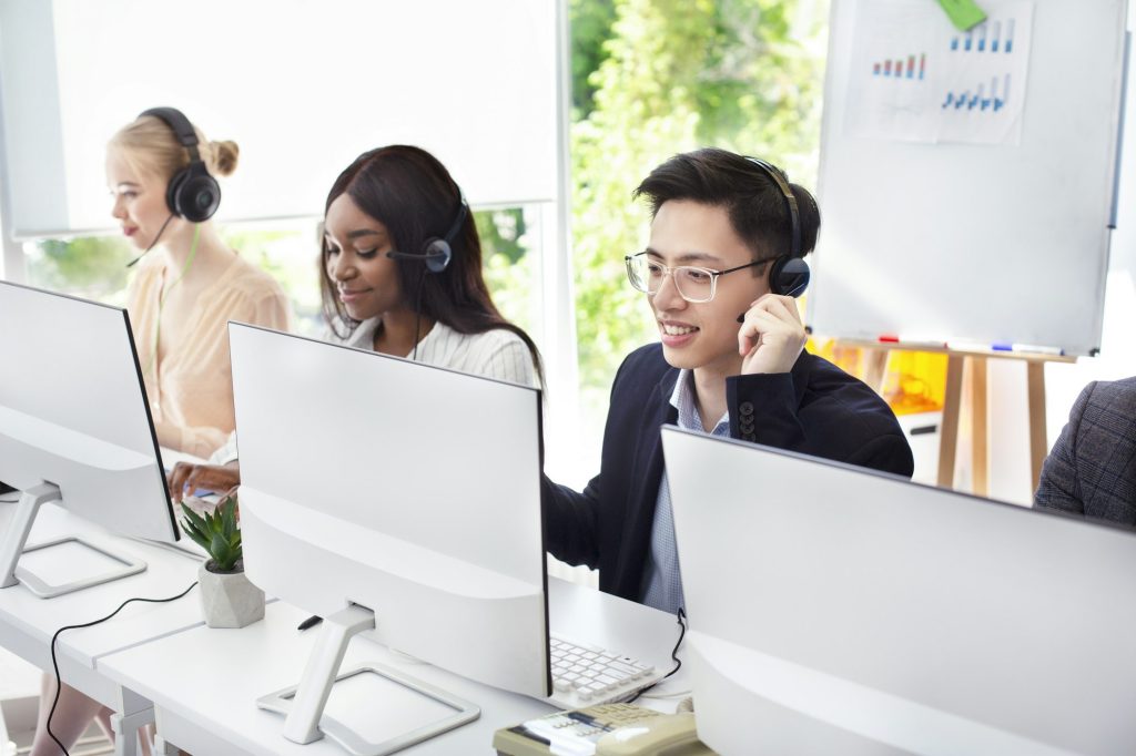 Team of helpline operators with headsets consulting clients at call center