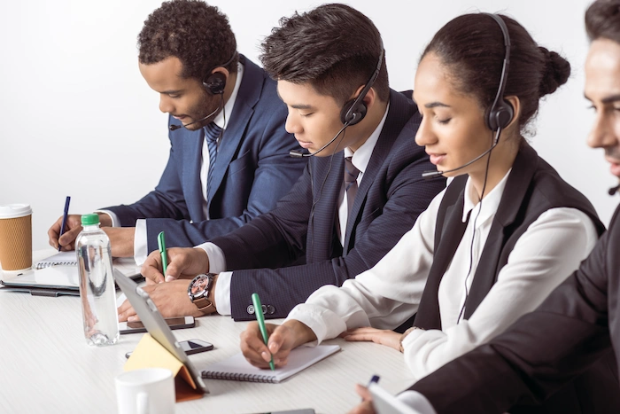 telemarketing group of professional telemarketers in a meeting writing notes