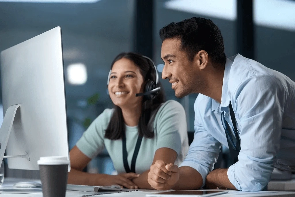 two employees checking on their outsourced customer service on a computer