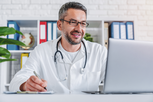 adult male doctor working on laptop writing