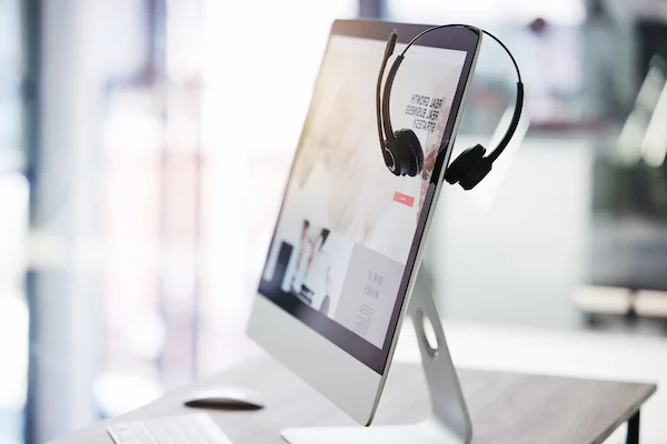 closeup of headset hanging on a computer e1728612701626