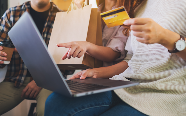 group of young people using laptop and credit card