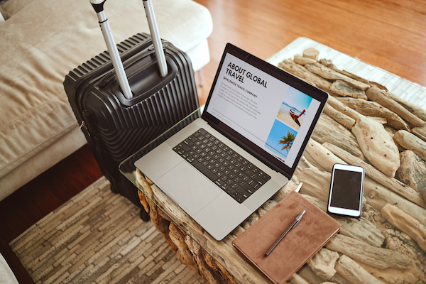 laptop screen travel website and suitcase