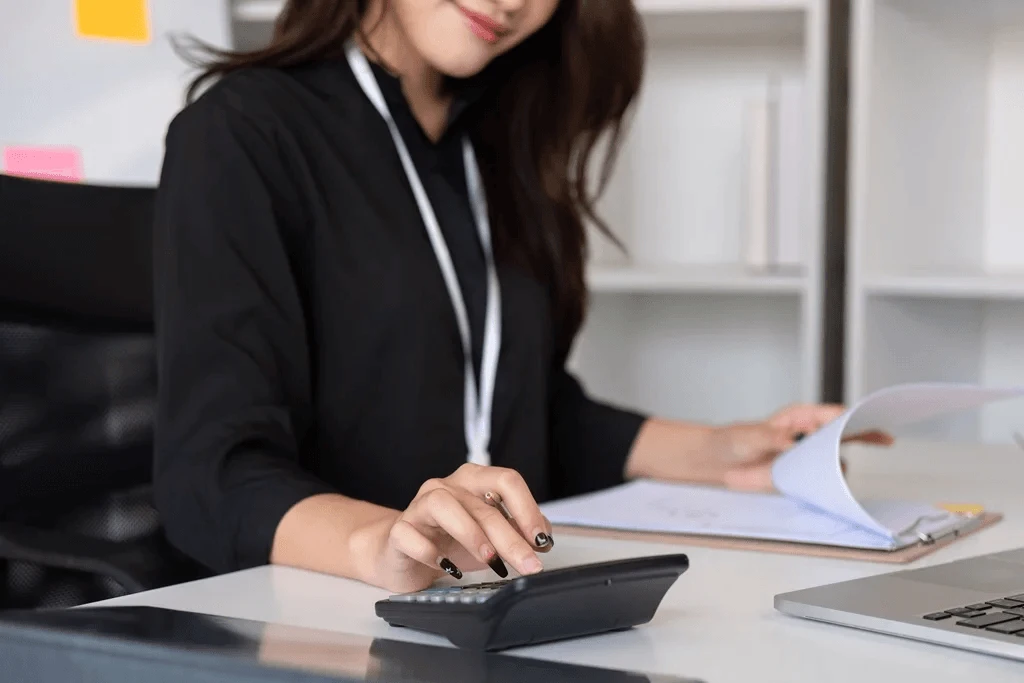 bookkeeping professional using a calculator and a laptop