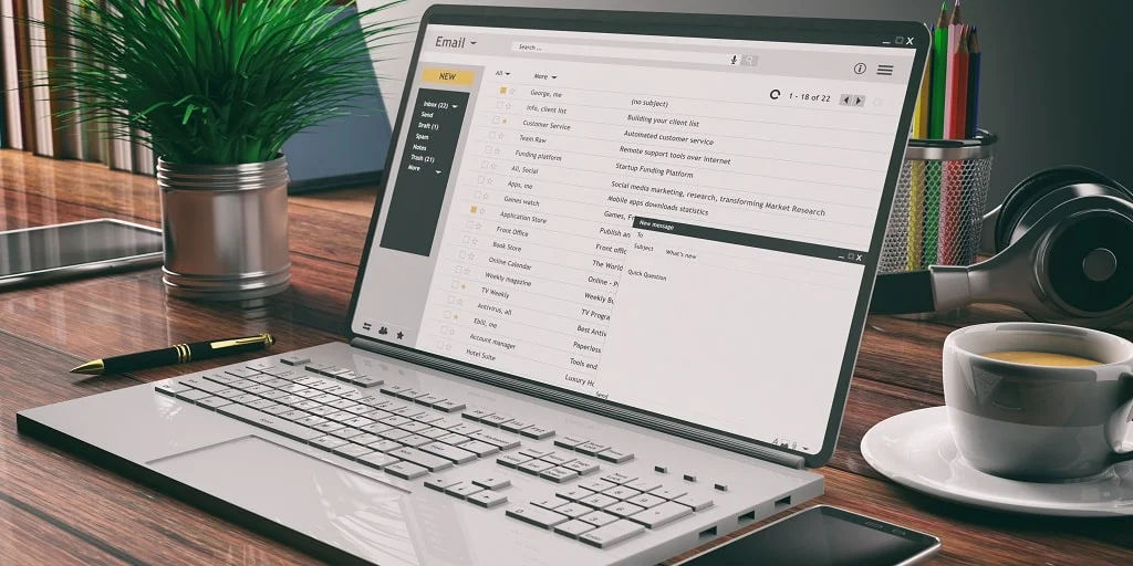 emails on a laptop screen wooden desk office
