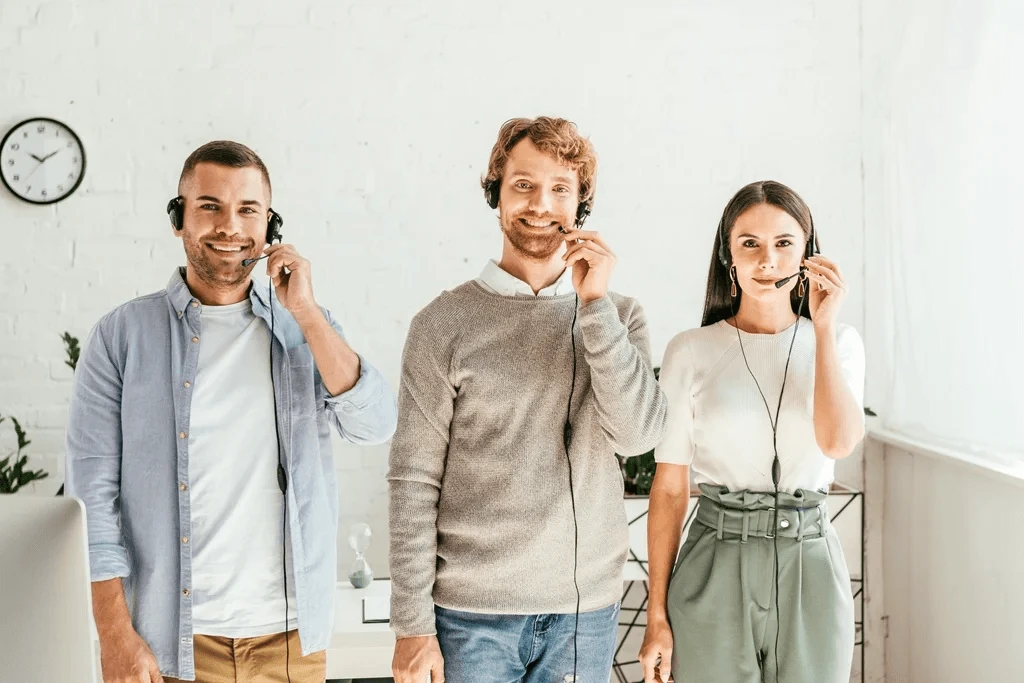 cheerful telemarketers in headsets standing