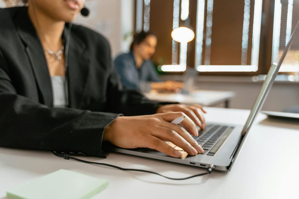 Call center agents working on laptops in a modern office setup.