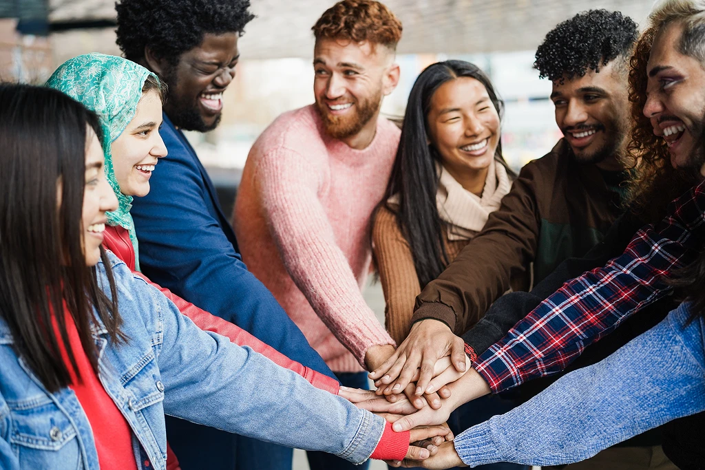 young diverse team having fun stacking hands outdoor