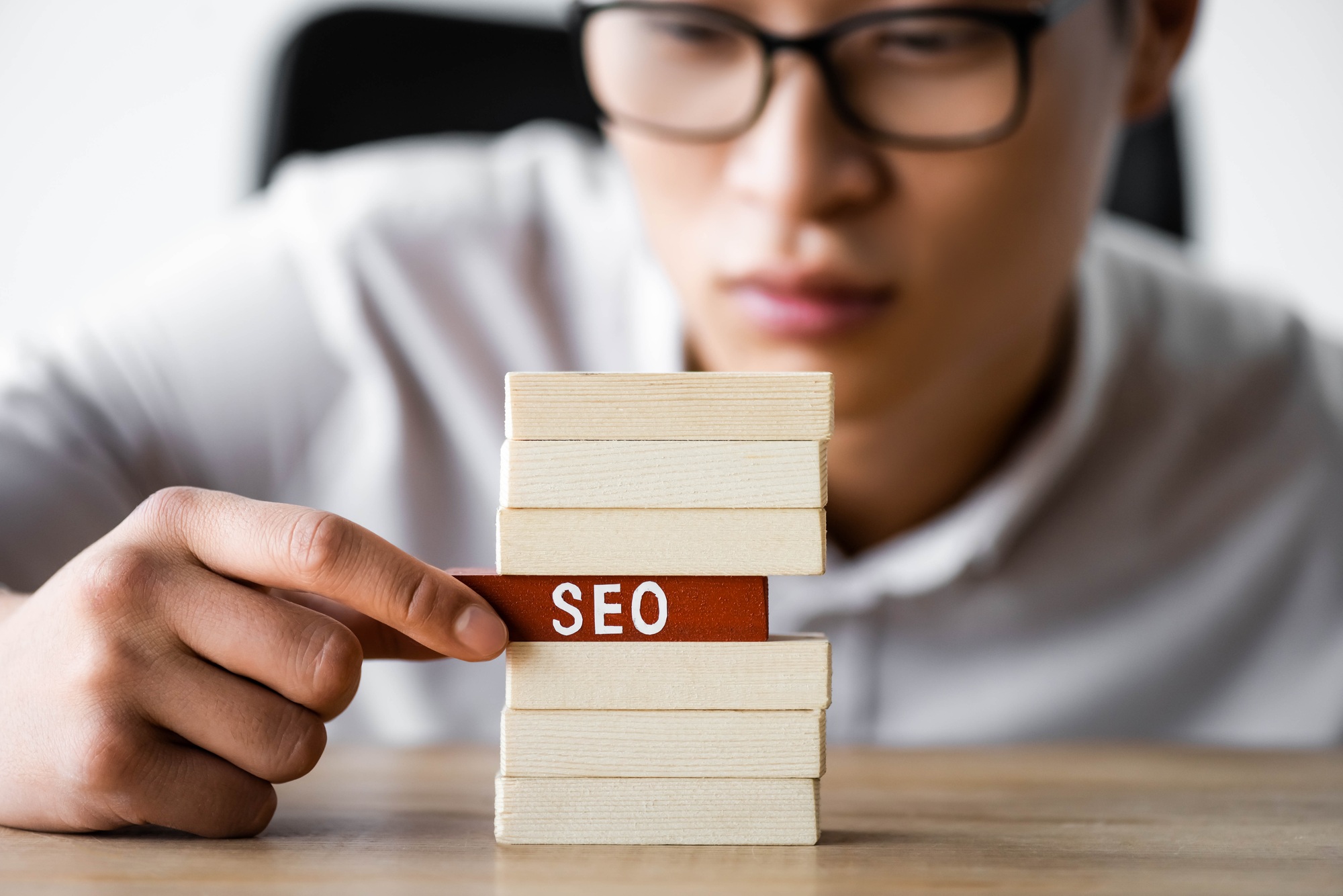 selective focus of asian seo manager holding wooden rectangle with lettering seo