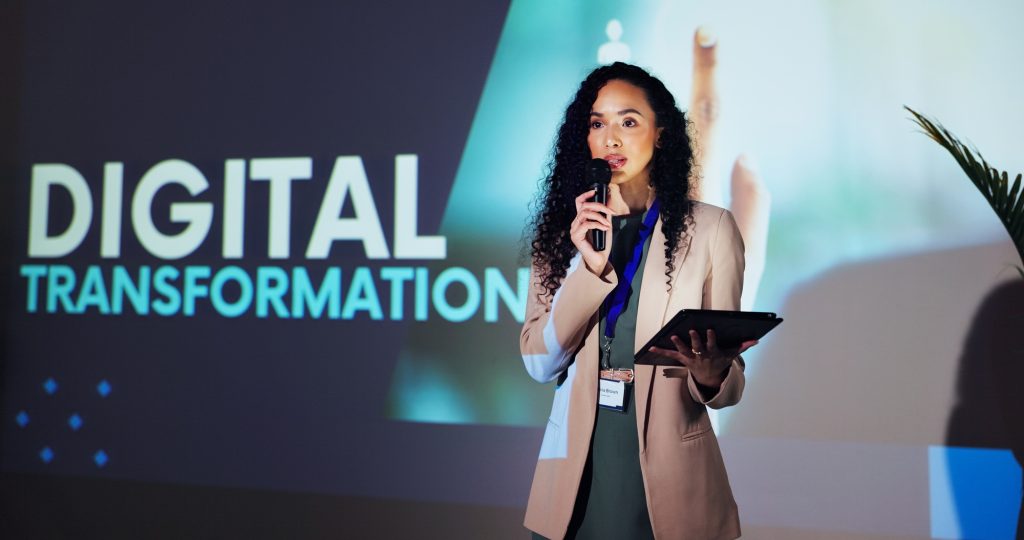 Stage, speaker and woman at seminar with microphone, tablet and presentation on digital transformat