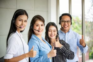 Team of diverse hotline operators with headphones providing service to clients at call center.