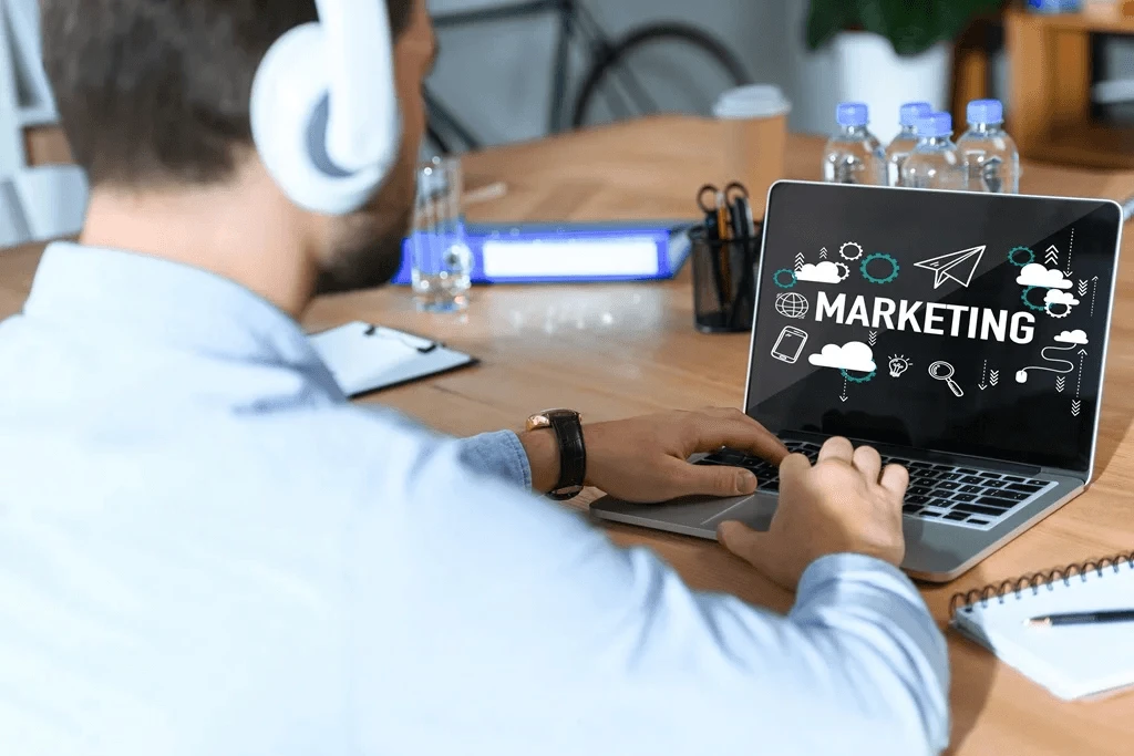 marketer using a laptop featuring icons about digital marketing campaigns