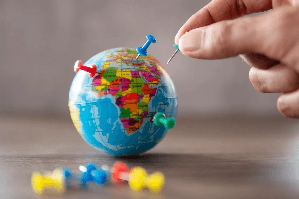 person putting pins on a globe symbolizing expansion