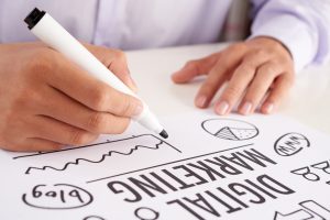 Crop hands making notes on digital marketing scheme