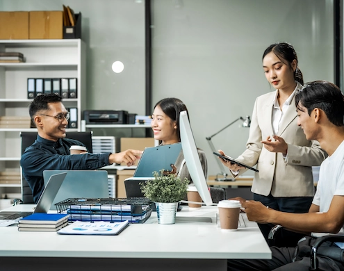 colleagues meet at a desk discussing business