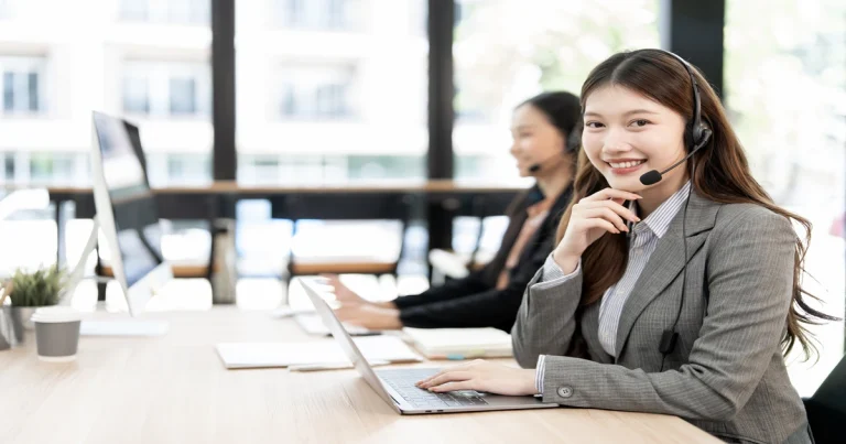 A smiling call center agent in a bright office setting, showcasing empathetic customer service traits.