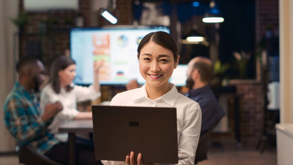 An SEO professional holding laptop at a team meeting